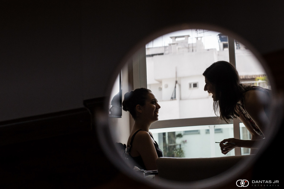 noiva e maquiadora vistas pelo reflexo de espelho redondo