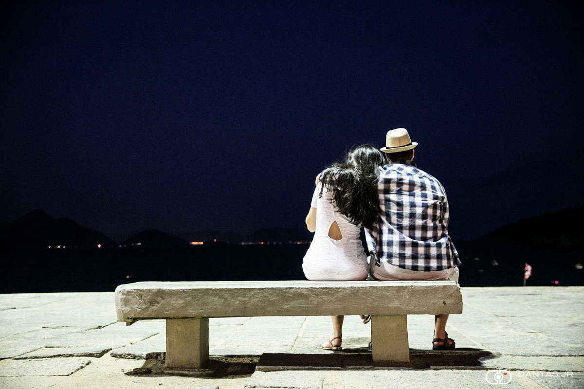 casal sentado em banco na Praia Vermelha olhando o mar