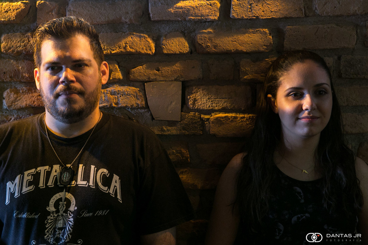 casal olhando pra frente encostados numa parede de tijolos no Lucky Screw Irish Pub em Copacabana