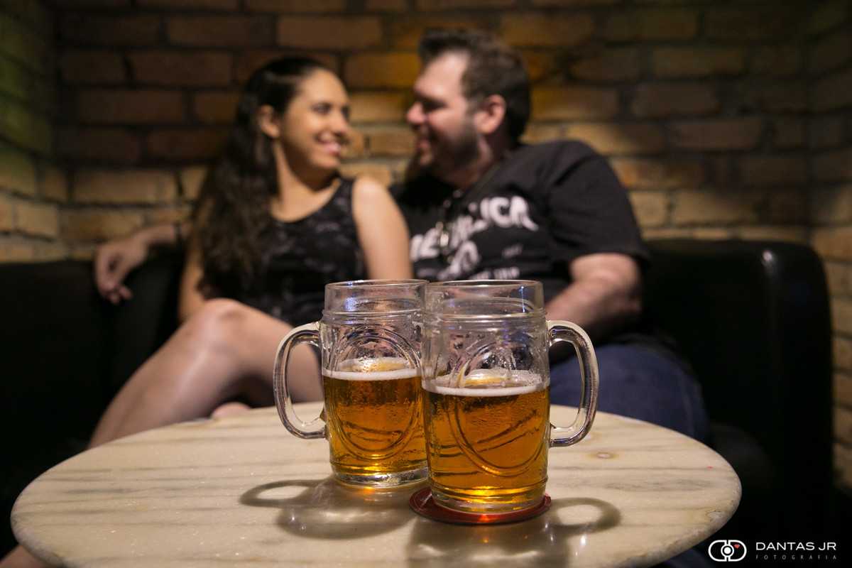 canecas de chopp em primeiro plano e casal namorando ao fundo desfocado em ensaio feito no Lucky Screw Irish Pub em Copacabana no Rio de Janeiro por Dantas Jr.