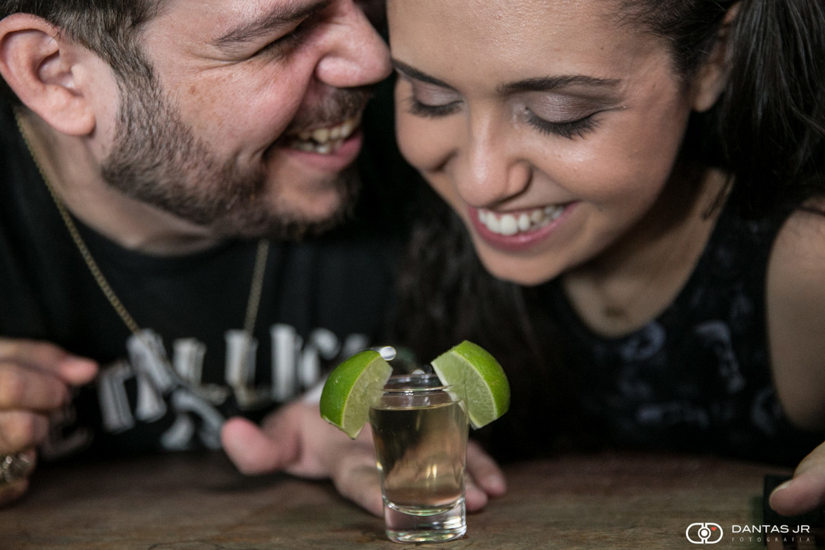 casal pronto para dividir um copo de tequila com limão rindo muito em pub em Copacabana no Rio de Janeiro por Dantas Jr