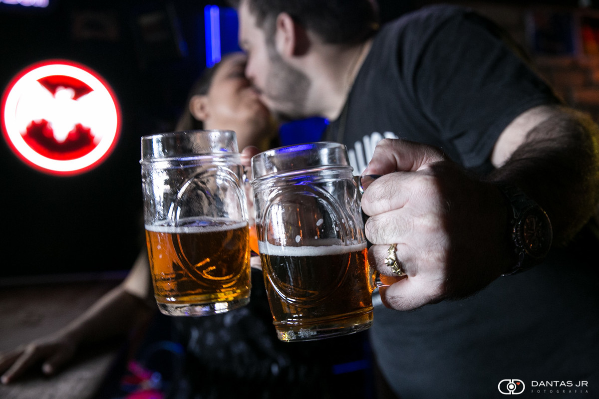 Casal brindando com canecas de chopp em pub