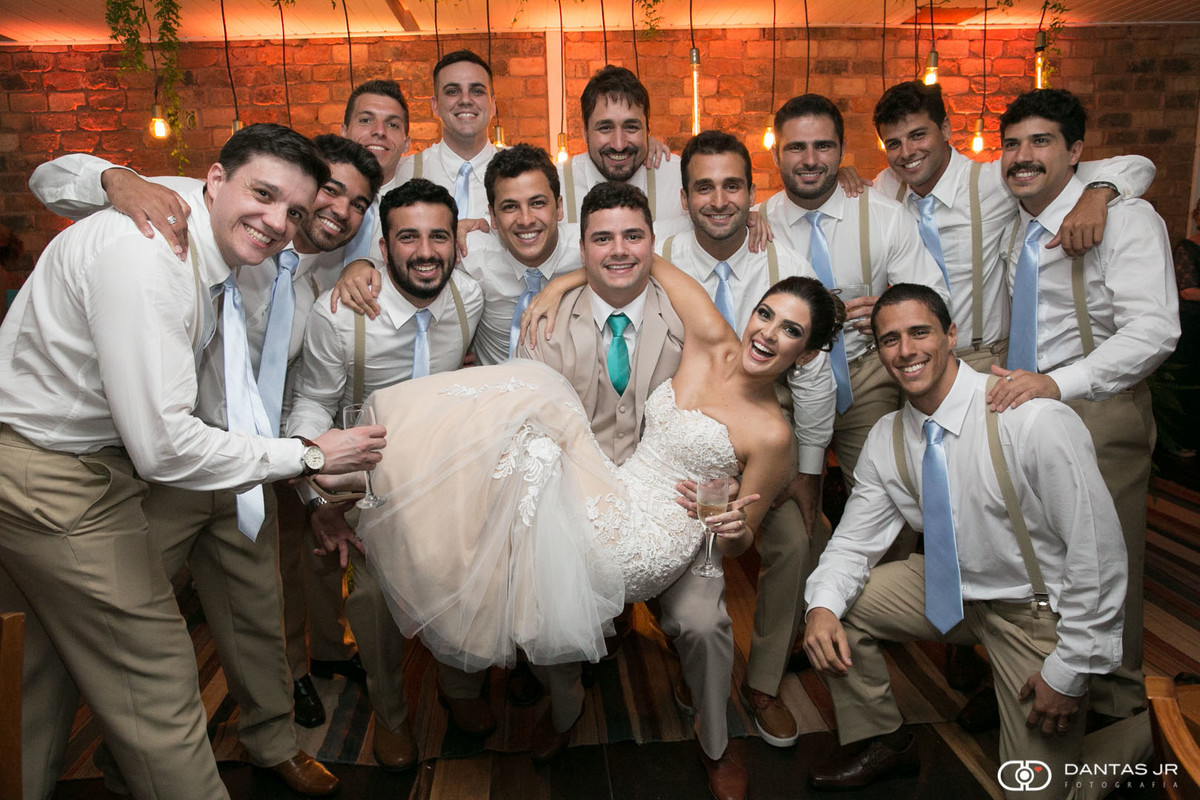 Noivo carregando noiva na frende de padrinhos em casamento no Restaurante Braseiro Américas na Barra da Tijuca no Rio de Janeiro por Dantas Jr.