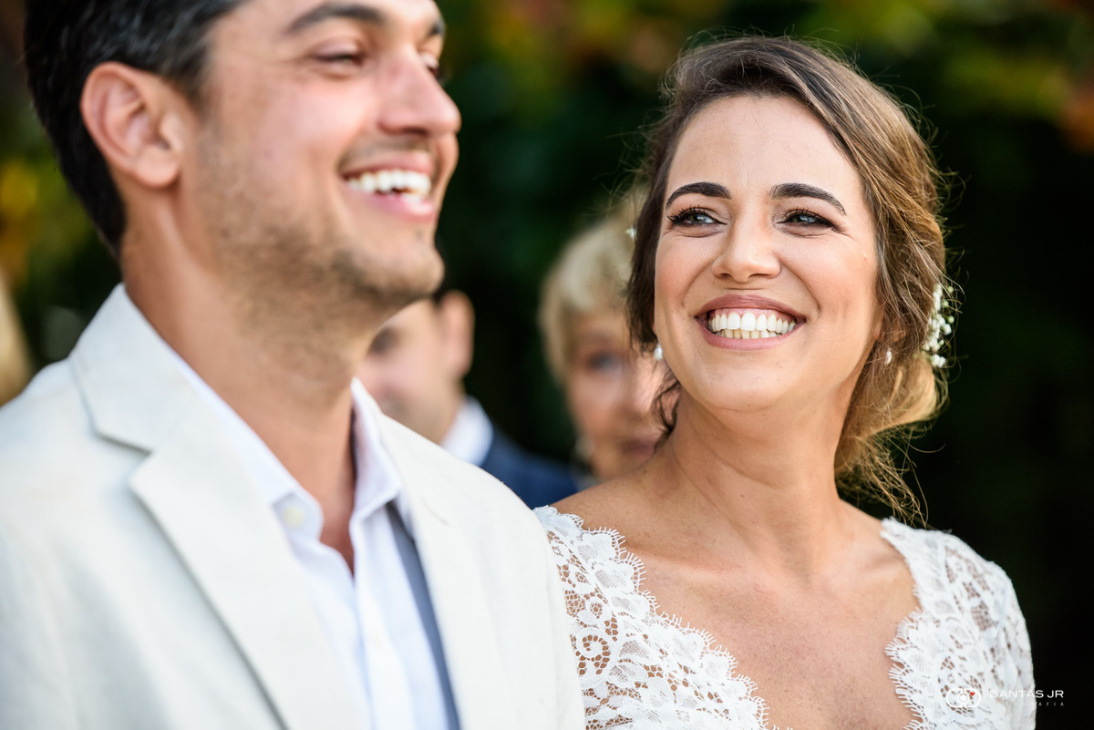 Noivos sorrindo em cerimônia ao por do sol em praia Destination Wedding em Angra dos Reis