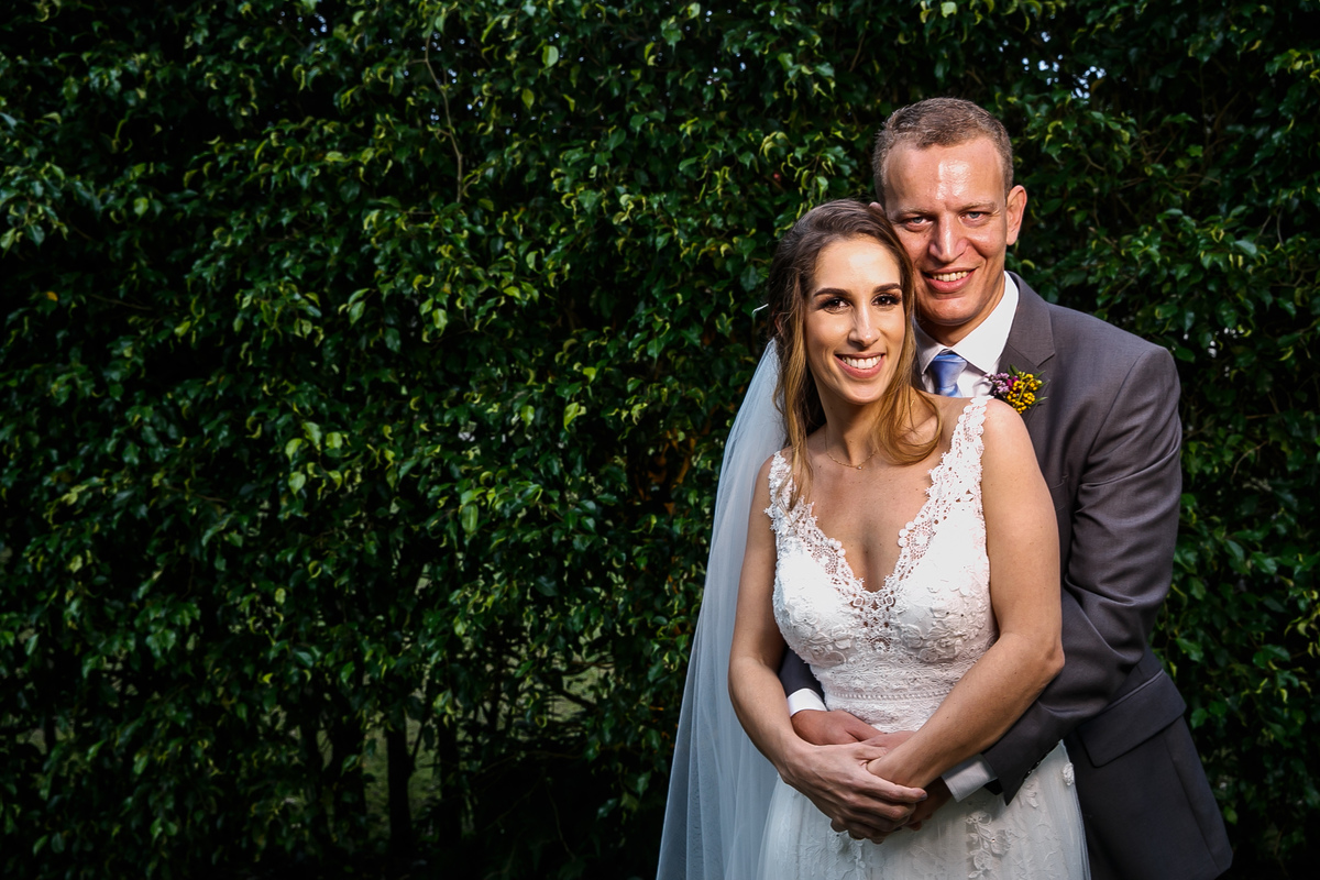 Retrato de noivos em frente a parede de cerca viva em casamento no campo ao ar livre Lajedo