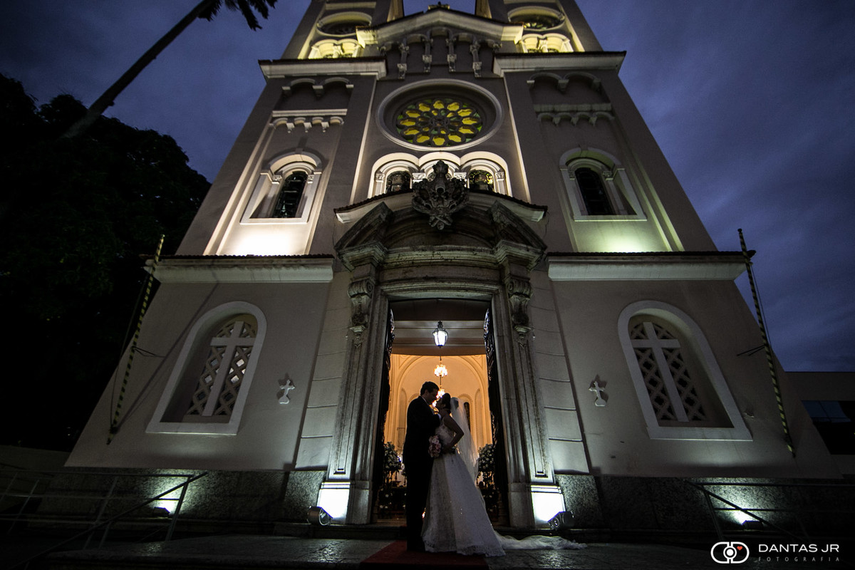 Noivos se beijando na frente da igreja São Pedro com por do sol ao fundo por Dantas Jr.
