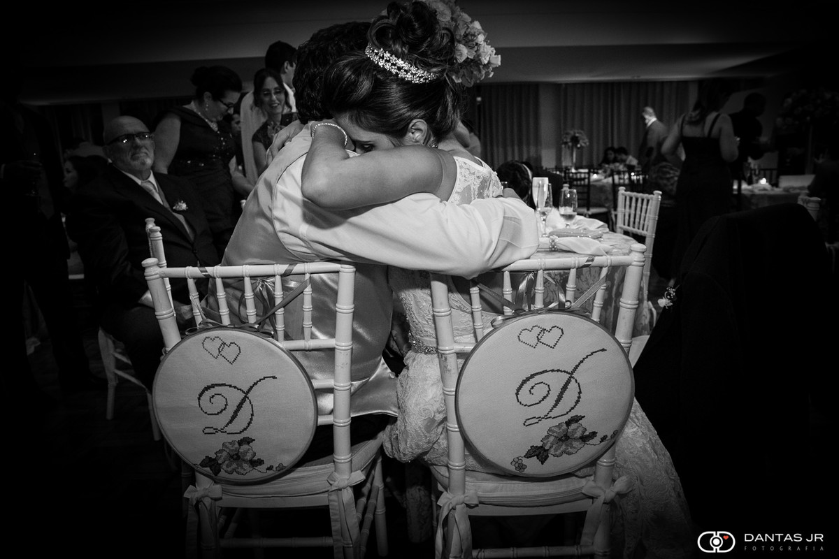 Casal de noivos abraçados em cadeira durante festa de casamento na Casa do Minho no Cosme Velho por Dantas Jr