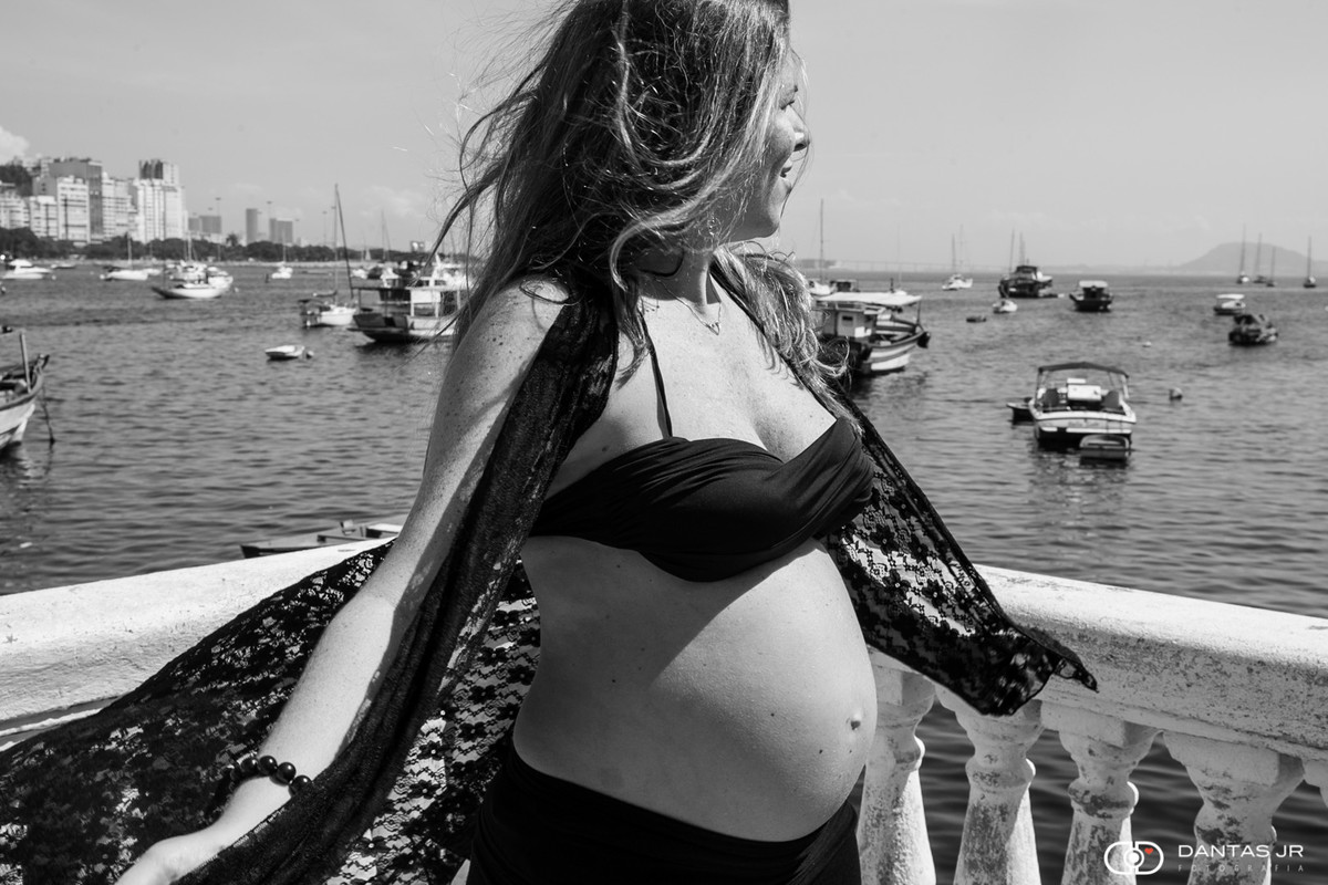 Grávida de roupa preta brincando ao vento na Urca no Rio de Janeiro com barriga de fora por Dantas Jr. Fotografia