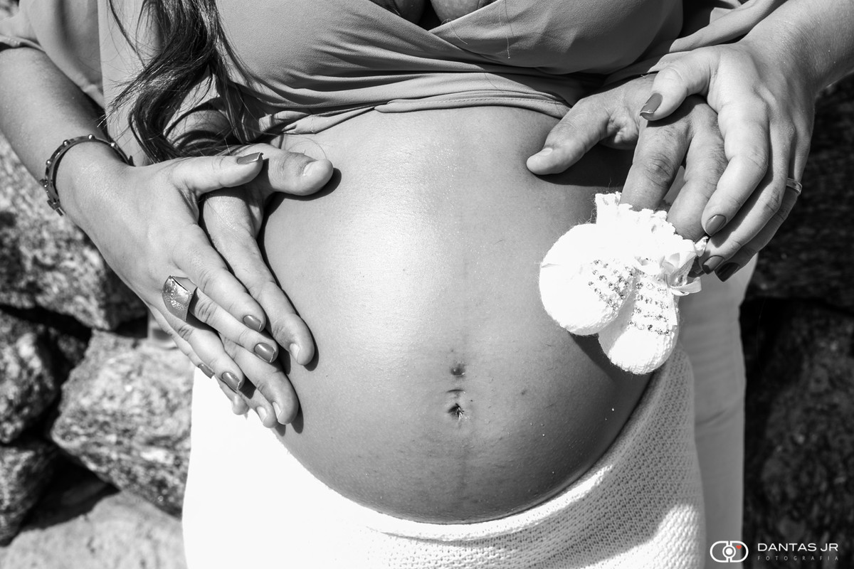 barriga de gravida com mãos dos pais segurando sapatinho de croche por Dantas Jr Fotografia
