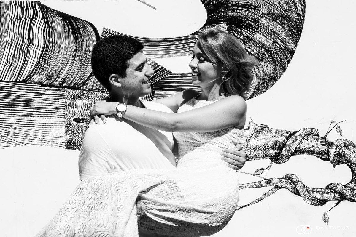 casal namorando ele carregando ela nos braços em frentee a muro grafitado no aterro do flamengo no Rio de Janeiro por Dantas Jr