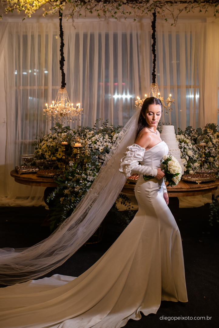 Noiva faz pose para foto na mesa do bolo no casamento em caratinga