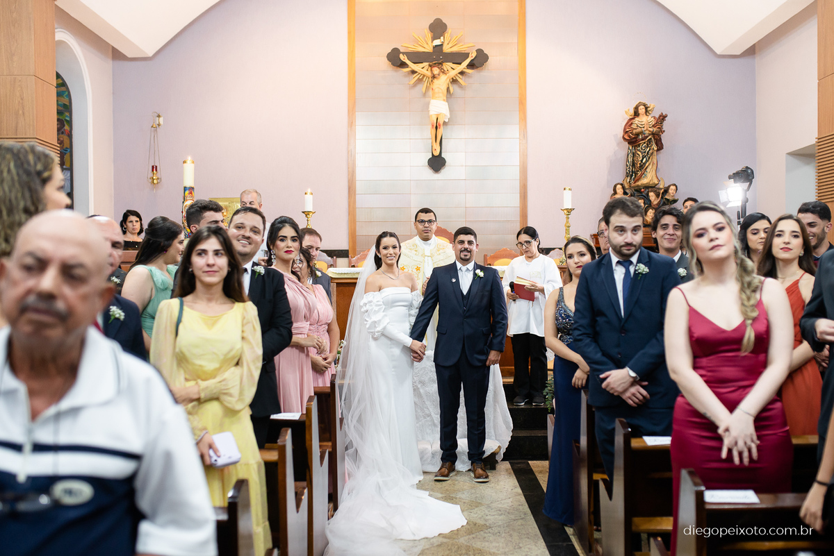 Noivos olhando a daminha entrar no casamento em caratinga