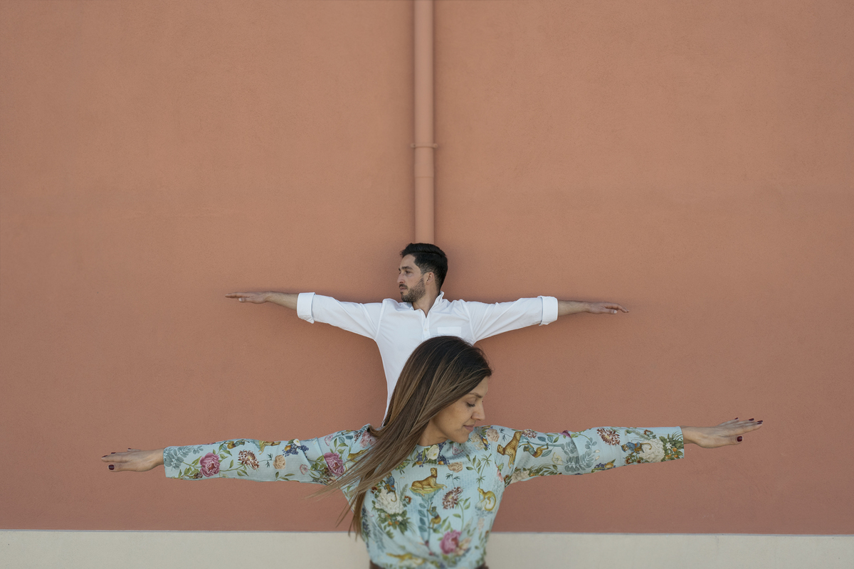 Noivos numa parede em Aveiro com os braços esticados de forma simétrica