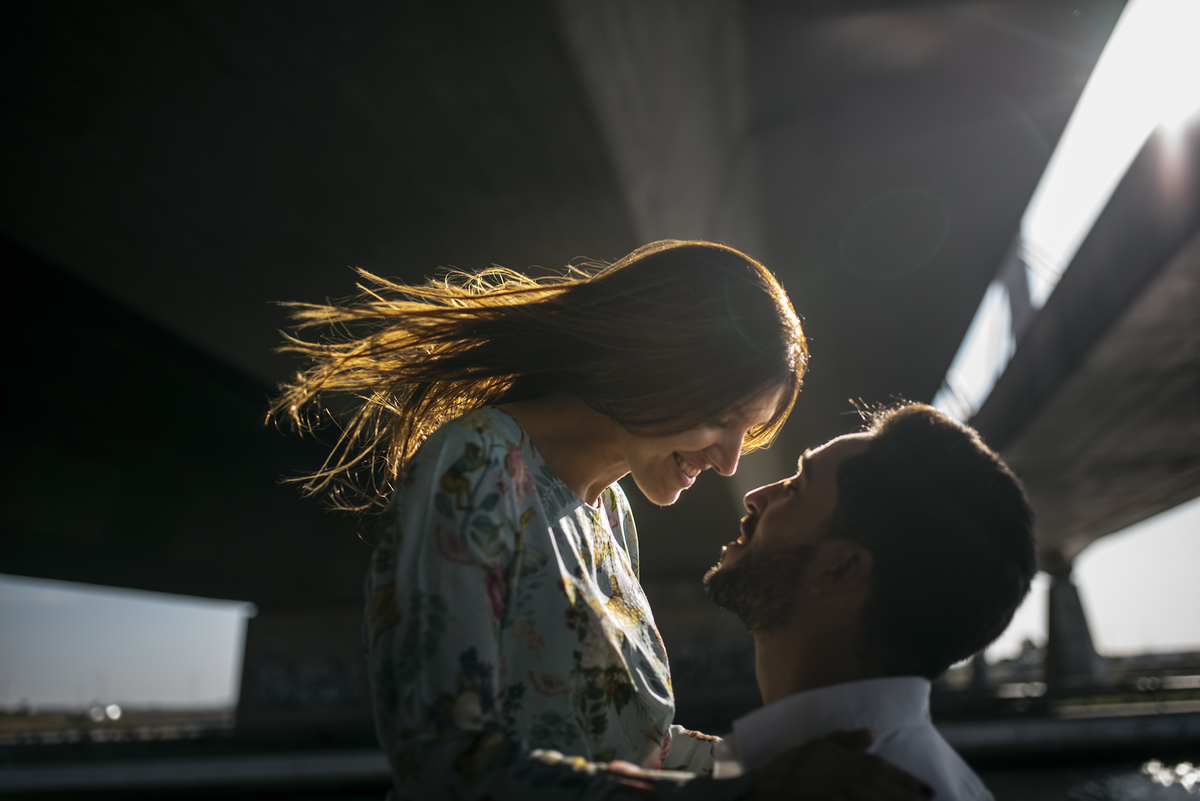 noivos olhando um para o outro com o cabelo dela a brilhar num raio de luz 