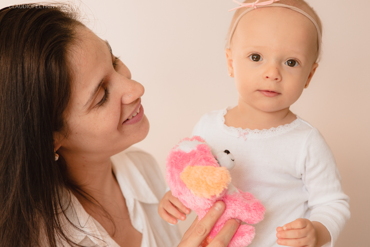 Mãe segurando o bichinho para filha no ensaio fotografico