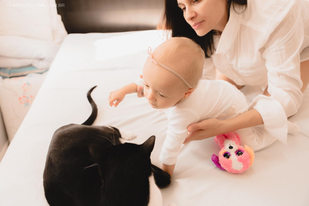 O gatinho veio participar do ensaio fotográfico com a criança e a mãe segura ela