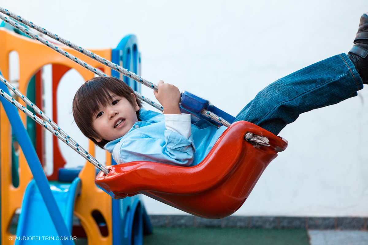 menino balançando bem alto e olhando para a câmera do fotografo 