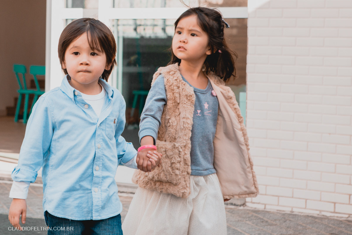 menino e menina andando de mãos dadas pela festa e a menina olhando para o que acontece ao lado