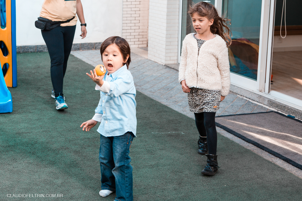 o menino acha um brinquedo, segura com a mão e abre a boca surpreso