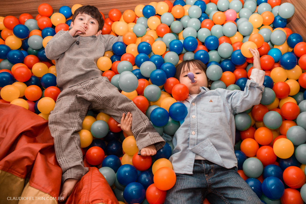 dois primos pulando na piscina de bolinhas e os dois com bexigas na coca