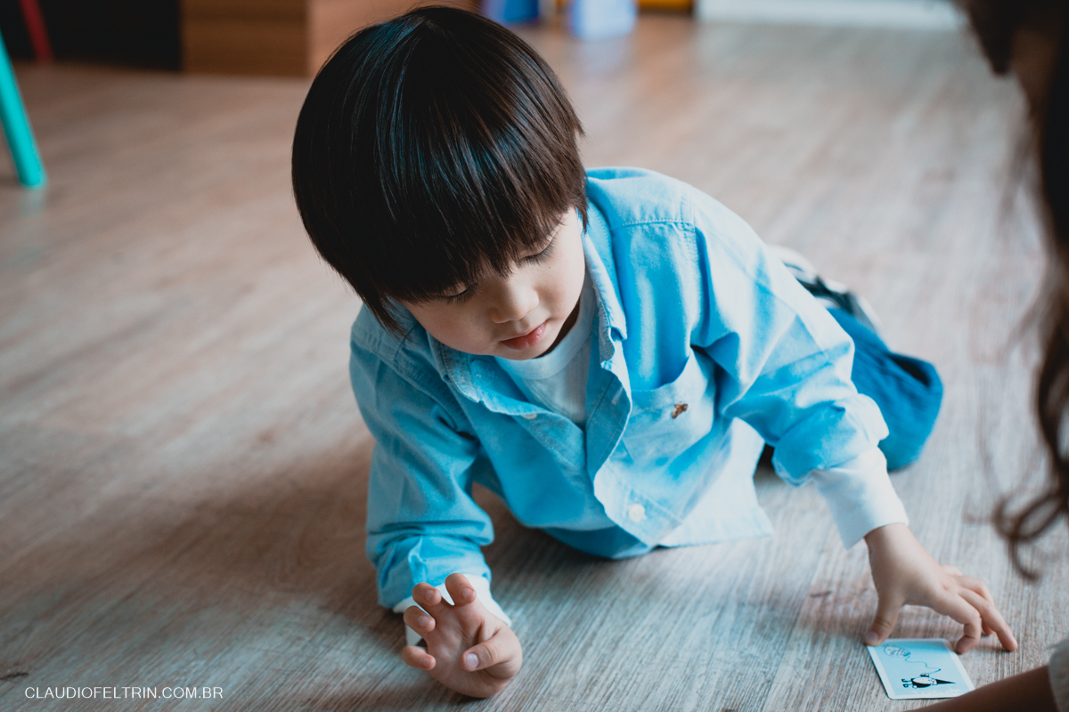 menino pegando baralho, esta deitado no chão