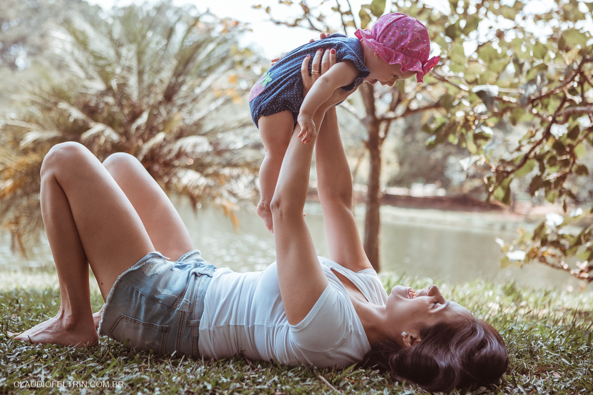 mãe deitada na grama levanta a filha ao ser fotografada por fotografo de são paulo