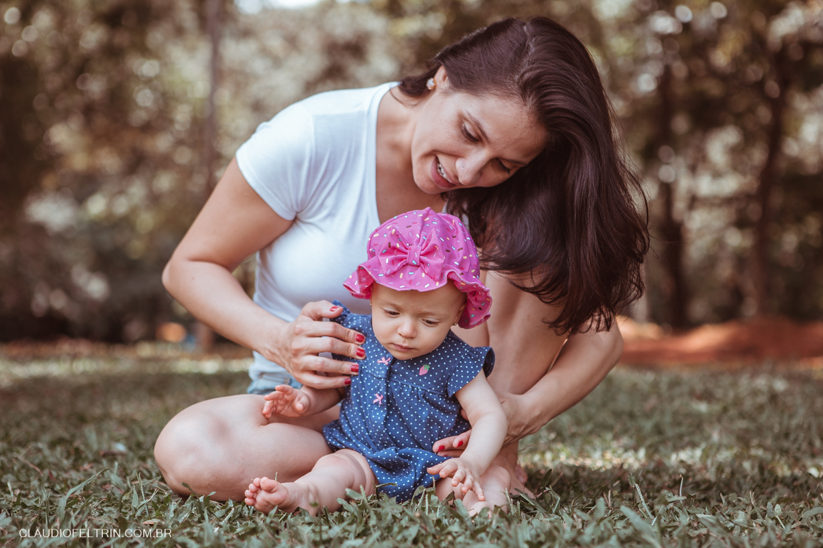 mãe segura a filha na grama para o fotografo claudio feltrin em parque de são paulo