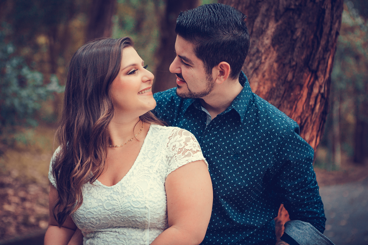 encostados em uma arvore os noivos se olham apaixonados em fotografia no parque da aclimação 