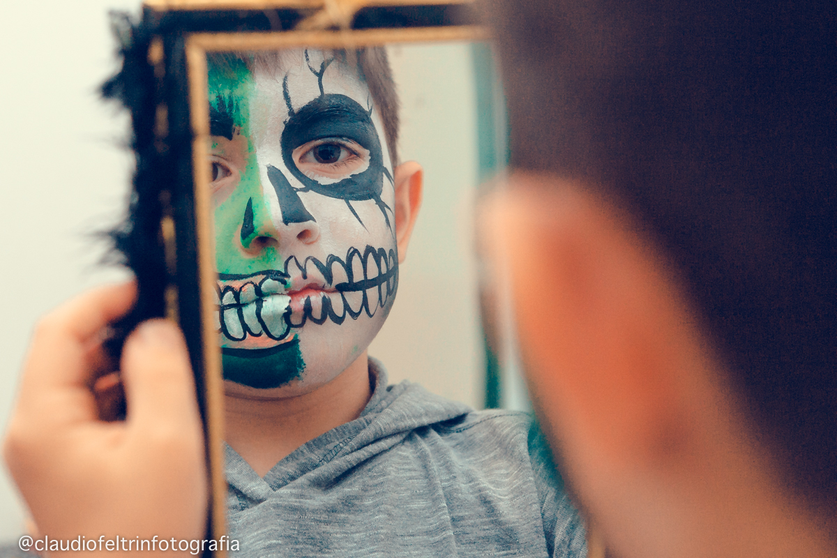 Menino olhando a maquiagem no espelho