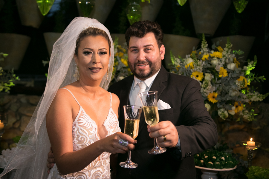 Noivos brindando na mesa do bolo