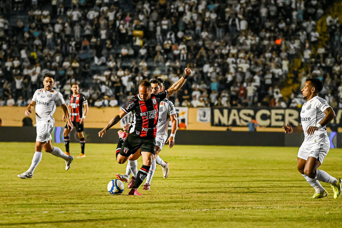 Jogador do Botafogo-SP avança contra a defesa do Santos FC no Estádio do Café, Londrina.
