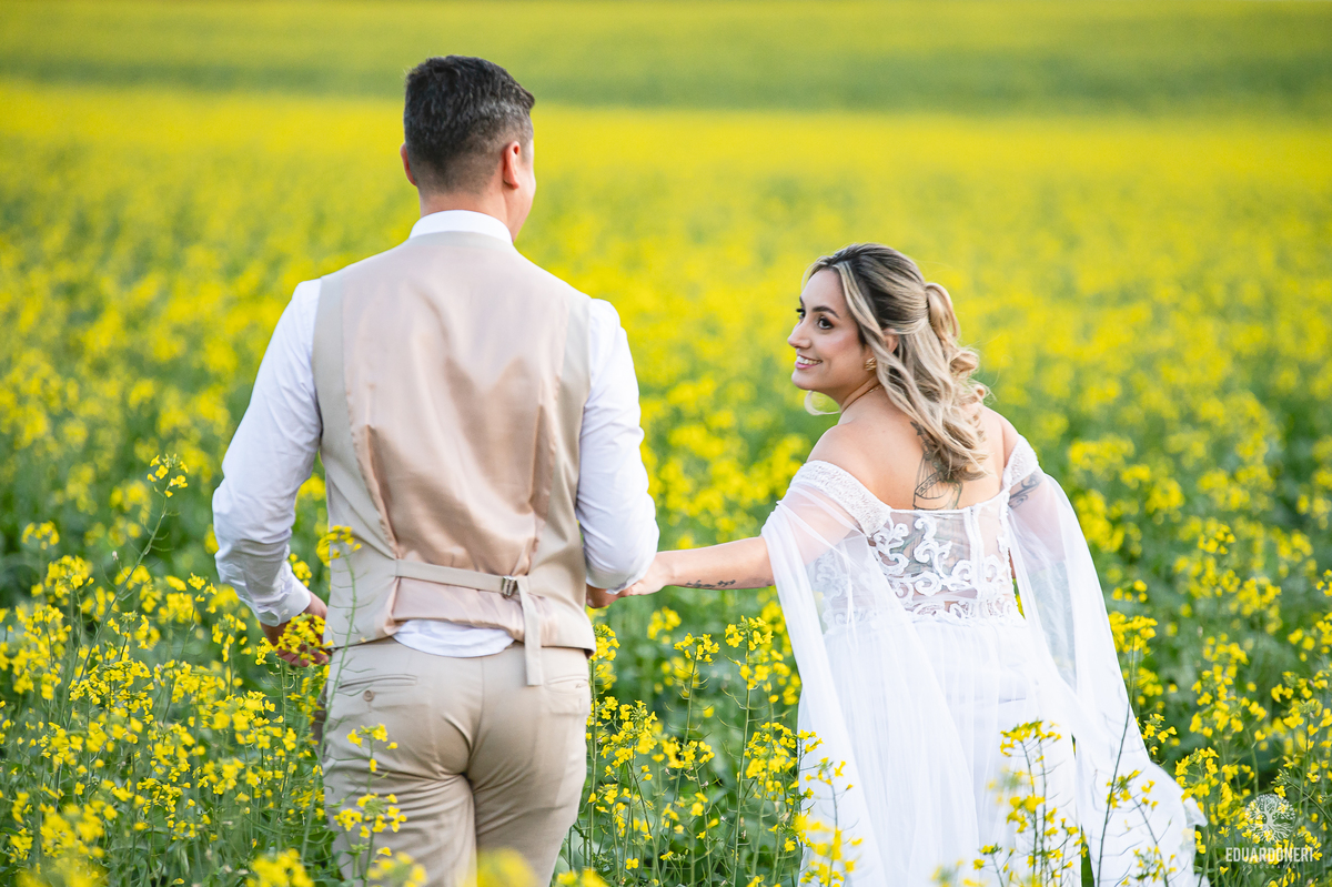 Noiva sorrindo entre flores amarelas do campo, em clima leve e natural