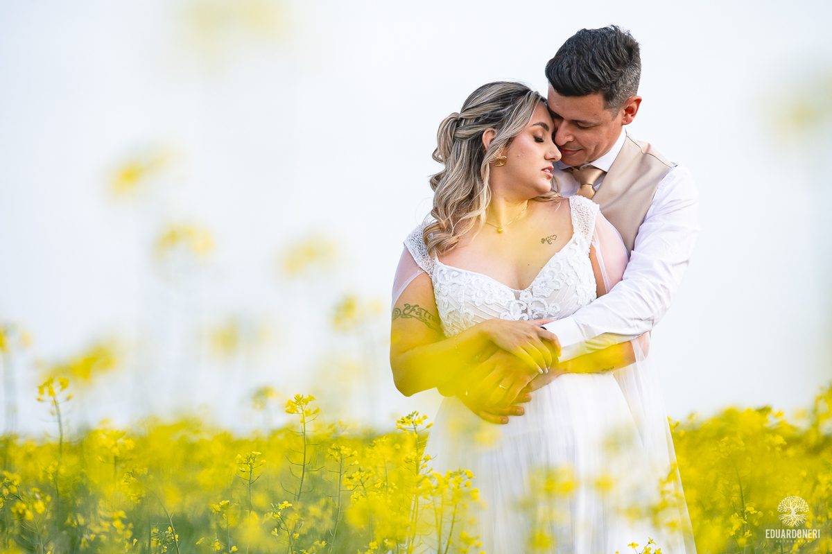 Casal se abraçando sob o céu alaranjado ao final de um Trash the Dress inesquecível