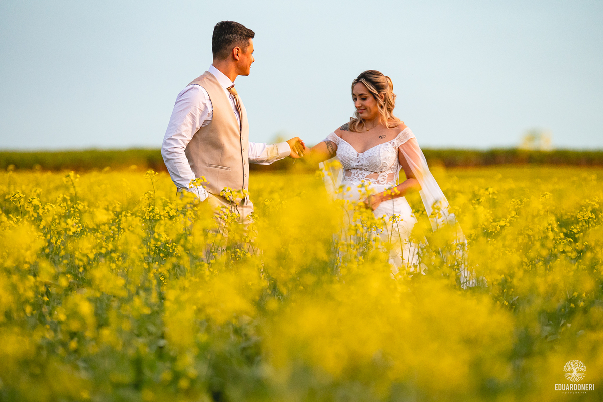 Noiva sorrindo entre flores amarelas do campo, em clima leve e natural