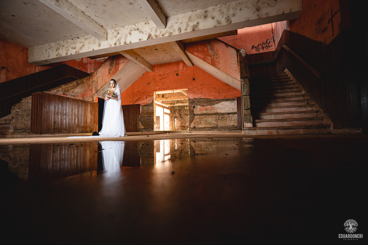 Noiva caminhando entre paredes de pedra no Hotel Yara, em ensaio fotográfico criativo Vestido de noiva contrastando com as paredes envelhecidas do Hotel Yara
