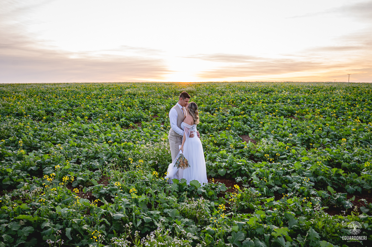 Beijo do casal em campo aberto ao entardecer, com pôr do sol dourado ao fundo