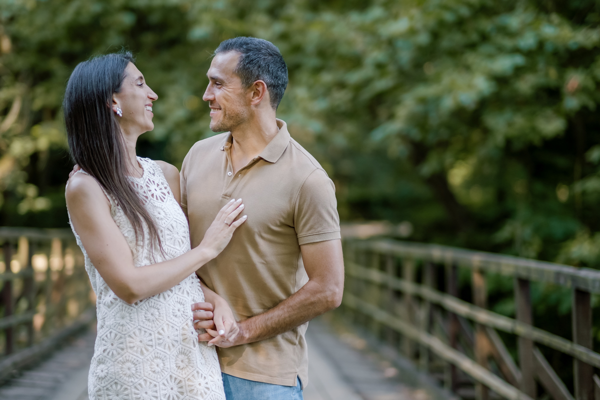 Casal sorridente em ponte de madeira durante sessão fotográfica de namoro em ambiente natural. Fotógrafo profissional de Cantanhede capta momentos autênticos e espontâneos.
 sessão de casal, fotografia de namoro, fotos românticas