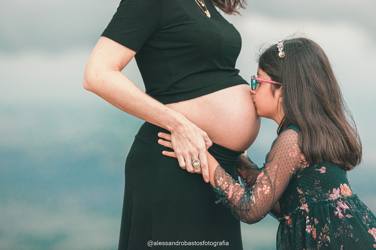 beijando a barriga a filha no ensaio sessao de fotos de gestante em bh e topo do mundo e moeda na cor azul