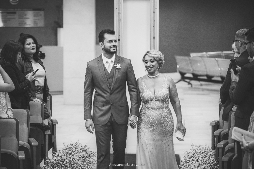 mãe do noivo do casamento em belo horizonte bh foto entra com o seu filho na cerimônia segurando uma bolsa branca