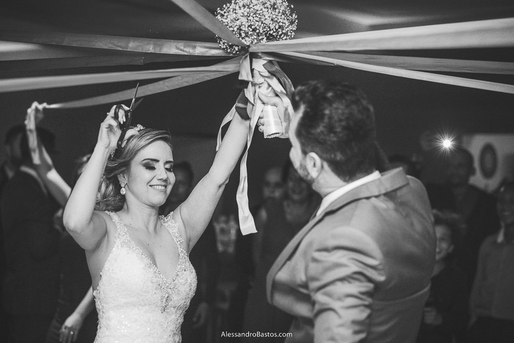 Simone noiva do casamento em belo horizonte bh foto corta o buquê de fitas com ajuda do noivo Alex