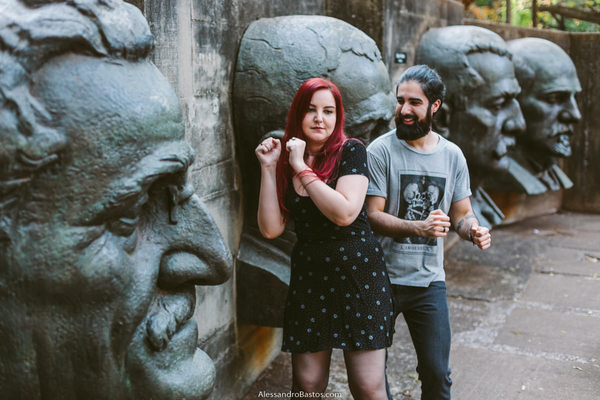 rostos de pedras são vistos com os noivos em sessão de fotografia pré-wedding antes do casamento em bh ao fundo do cenário