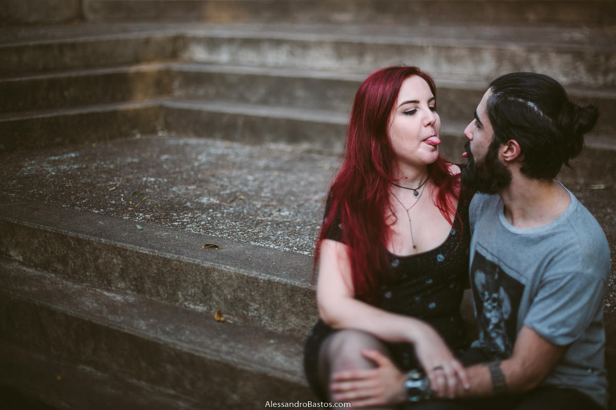 mostrando a língua estão os noivos em sessão de fotografia pré-wedding antes do casamento em bh enquanto a noiva senta no colo dele