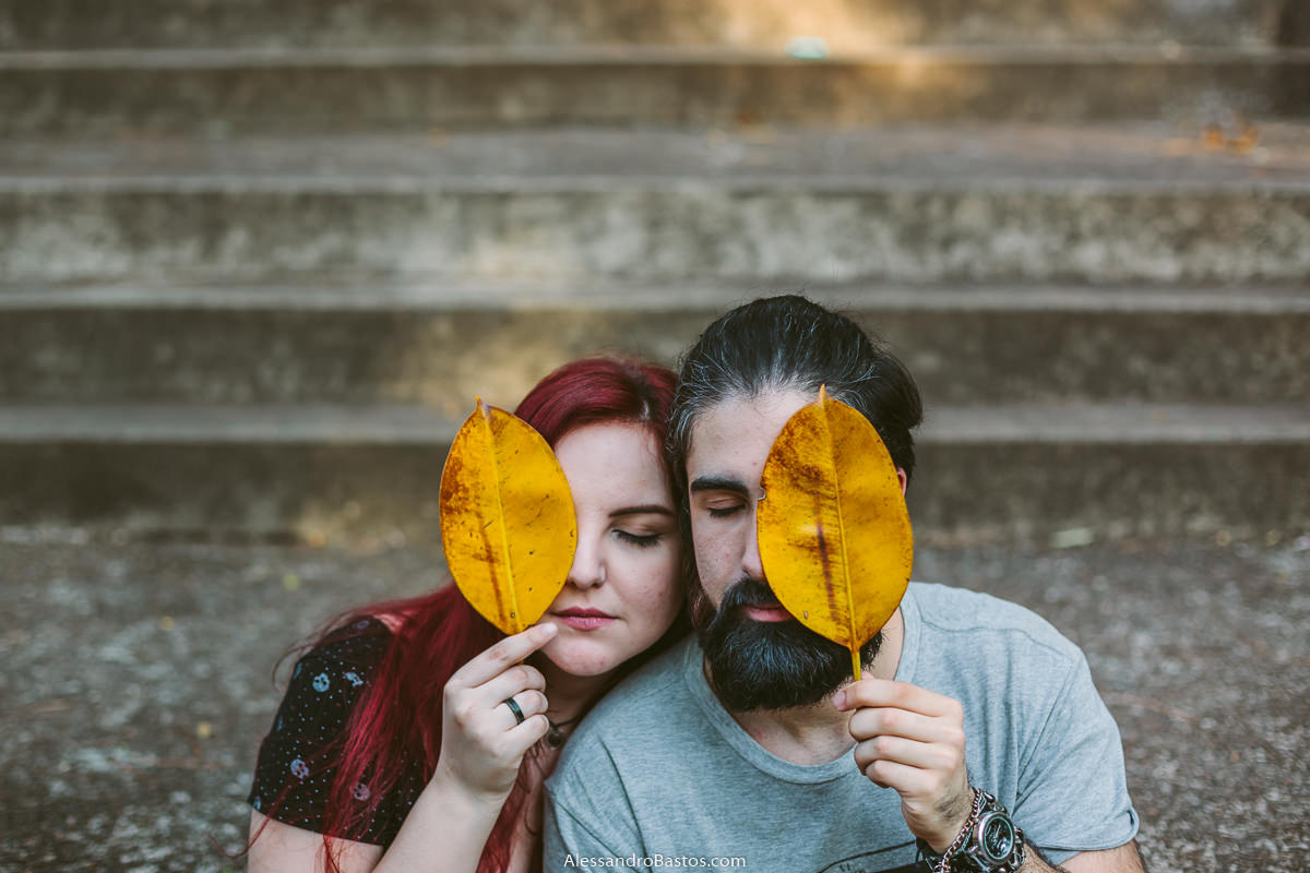 segurando folhas amarelas estão os noivos em sessão de fotografia pré-wedding antes do casamento em bh com o fundo sendo uma escadaria