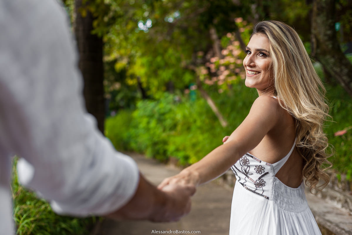de mão dadas os noivos no ensaio pre-wedding para a fotografia do casamento em bh seguem pelo caminho e ela olha pra ele