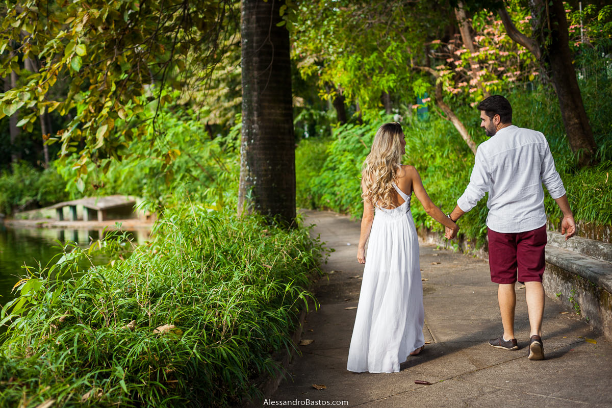 ela segura na mão dele e os noivos no ensaio pre-wedding para a fotografia do casamento em bh caminham pela mata