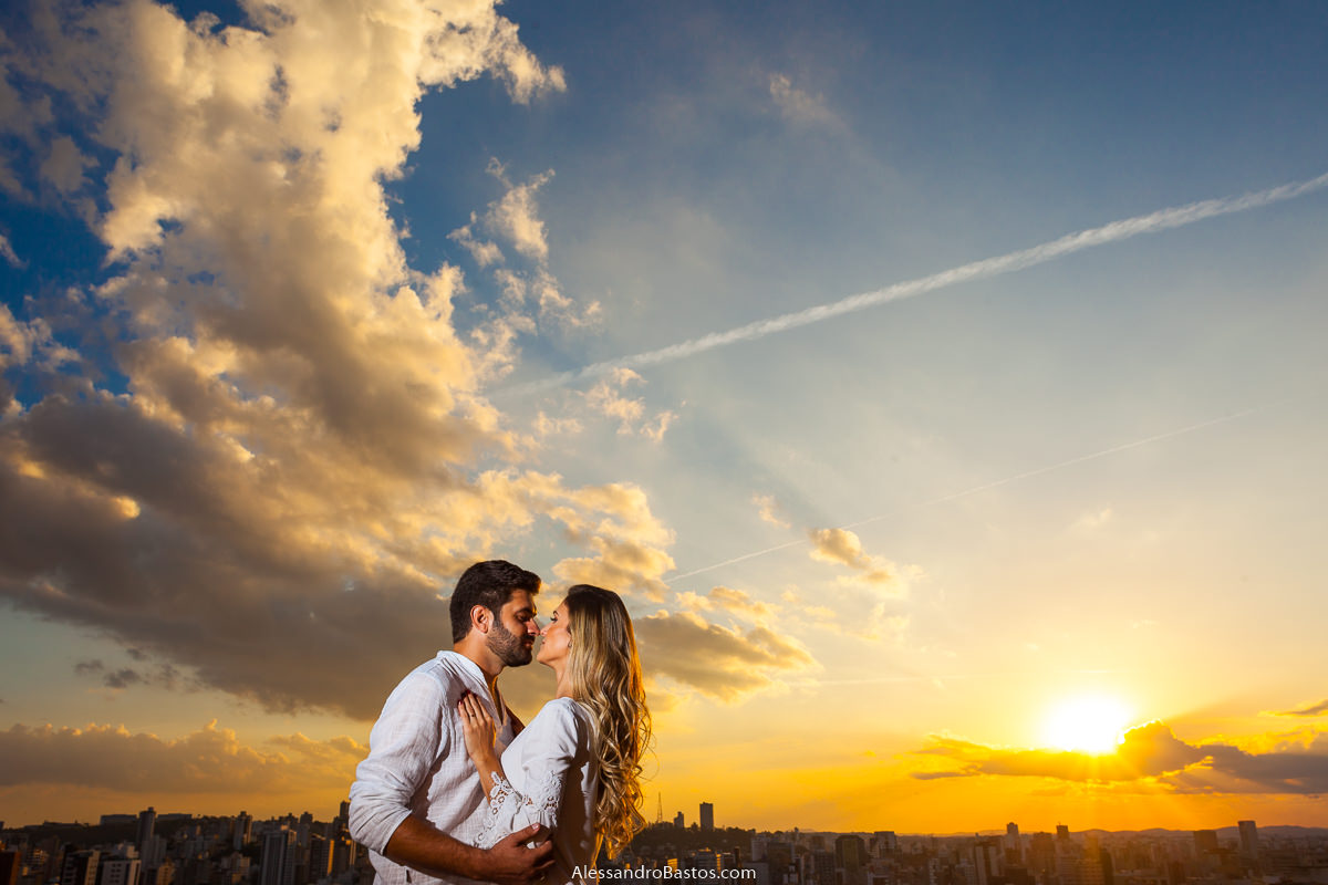 bem de frente um para o outro os noivos no ensaio pre-wedding para a fotografia do casamento em bh se beijam com o sol se pondo de cenário belíssimo