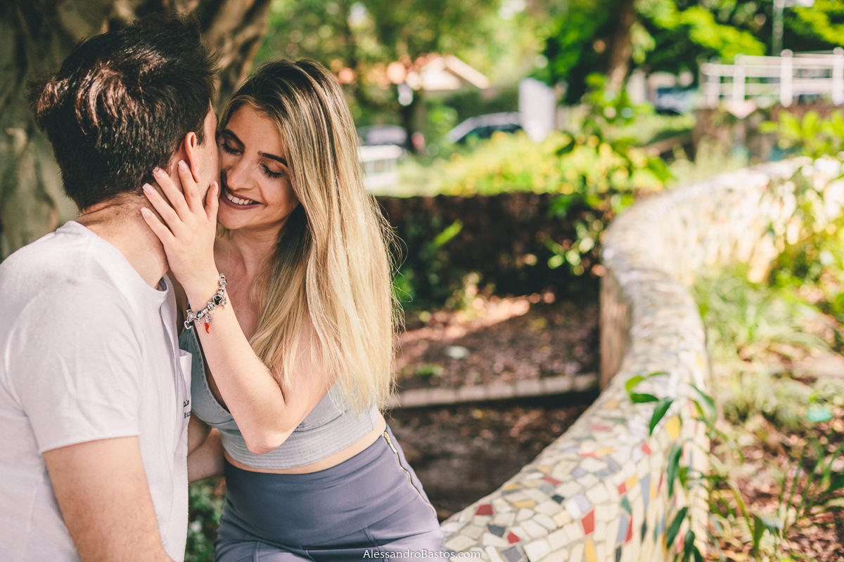 curva bem acentuada no canteiro de flores para fotografia pre-wedding fotografo casamento bh com os noivos sentados e ela coloca a mão no rosto dele