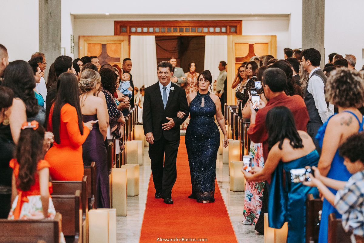 o pai do noivo e a mãe do noivo entram na igreja fotografo casamento bh pre-wedding pre-casamento pos-casamento fotografia belo horizonte igreja santo cura d'ars a mãe usando um vestido azul escuro