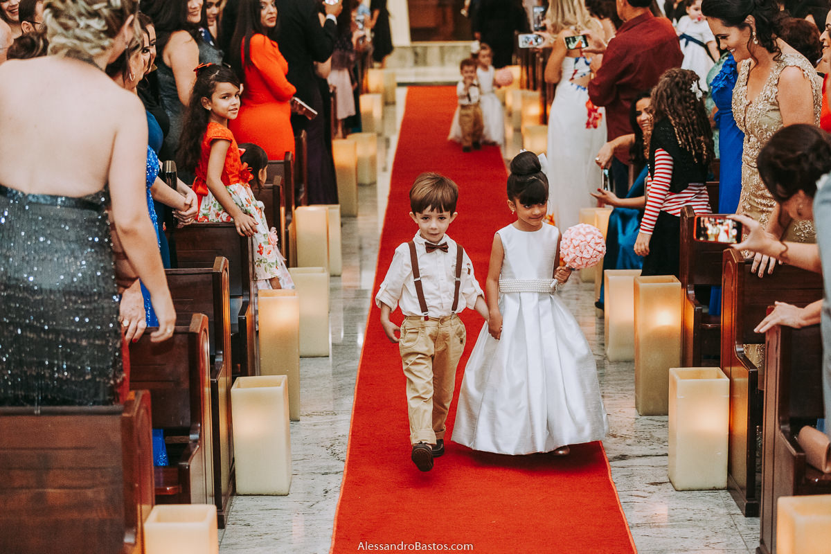 primeiro casal de damas e pajens entrando na igreja fotografo casamento bh pre-wedding pre-casamento pos-casamento fotografia belo horizonte igreja santo cura d'ars ele usa suspensórios e calça na cor marrom clara