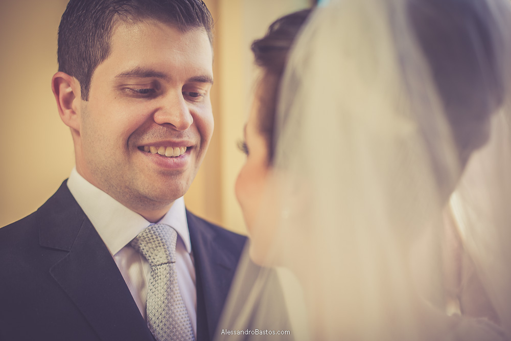 sorrindo está o noivo olhando para a noiva nas fotos do casamento em bh no buffet catharina dos noivos na fotografia em belo horizonte para o fotografo bh no museu de artes e ofícios e a noiva desfocada em primeiro plano
